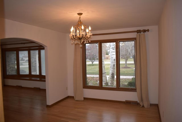 unfurnished dining area featuring wood-type flooring and a chandelier