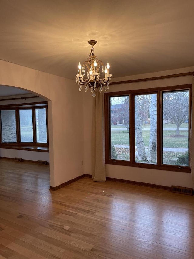 spare room featuring hardwood / wood-style flooring and a notable chandelier