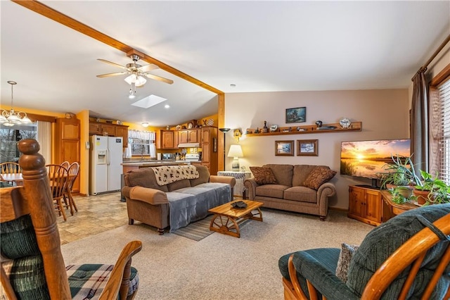 carpeted living room featuring ceiling fan with notable chandelier and vaulted ceiling with skylight