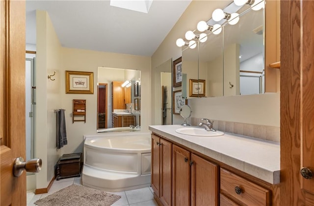 bathroom featuring a tub to relax in, a skylight, tile patterned flooring, and vanity