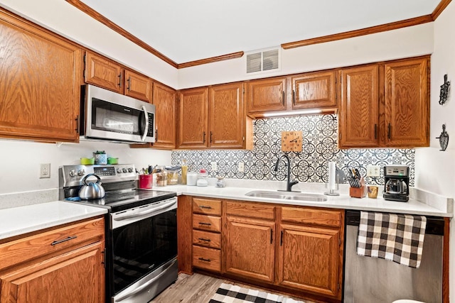 kitchen featuring sink, decorative backsplash, ornamental molding, stainless steel appliances, and light wood-type flooring