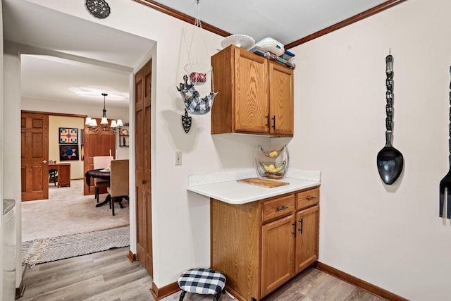 kitchen featuring pendant lighting, a notable chandelier, ornamental molding, and light wood-type flooring