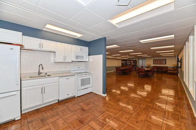 kitchen with dark parquet floors, white cabinetry, sink, decorative backsplash, and white appliances