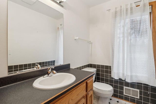 bathroom featuring vanity, toilet, and tile walls