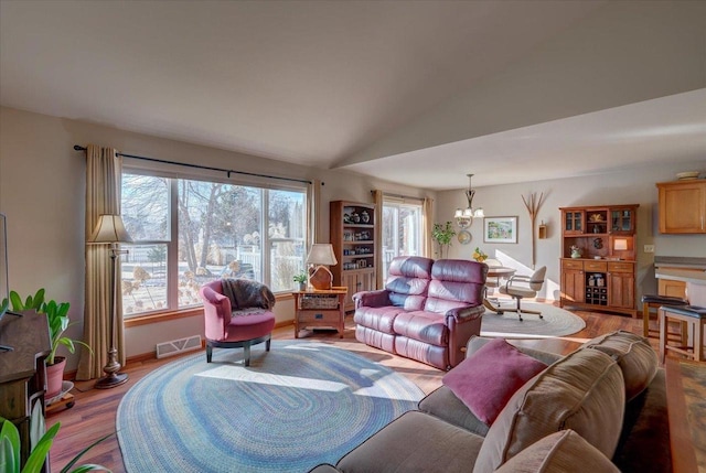 living room with lofted ceiling, a notable chandelier, and light hardwood / wood-style floors