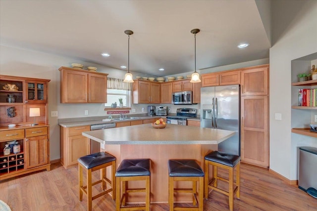 kitchen featuring a breakfast bar area, hanging light fixtures, stainless steel appliances, light hardwood / wood-style floors, and a kitchen island