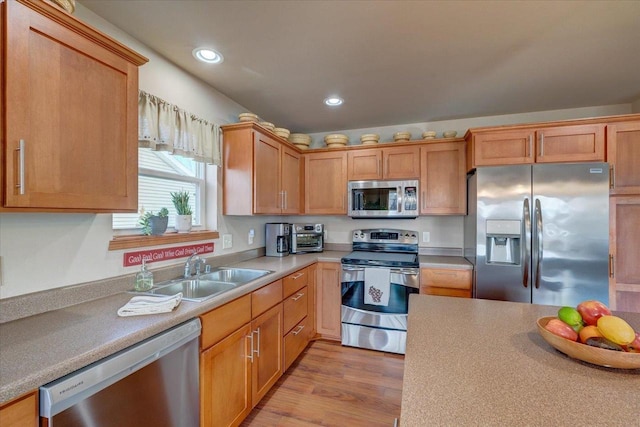 kitchen with stainless steel appliances, sink, and light hardwood / wood-style floors