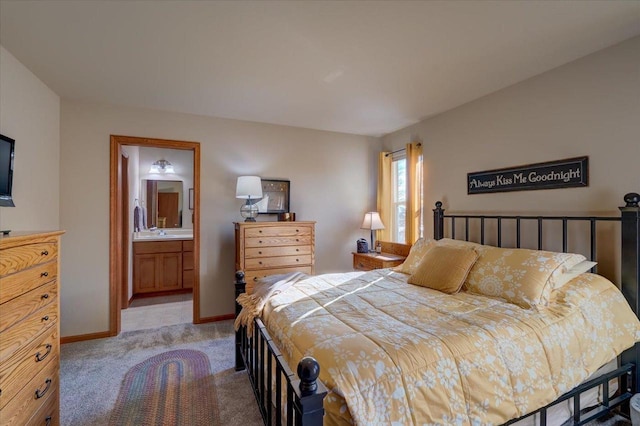 bedroom with ensuite bathroom, sink, and light colored carpet