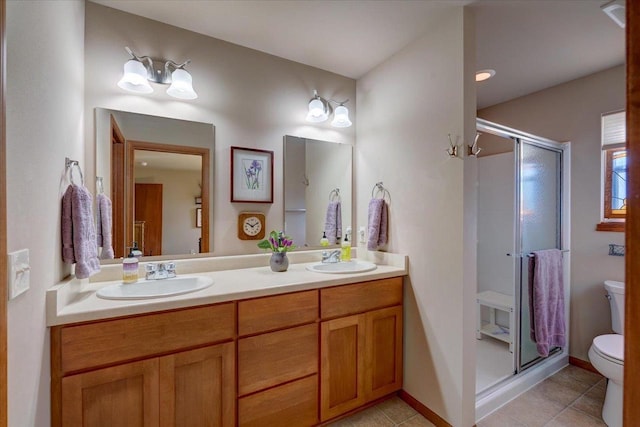 bathroom featuring tile patterned flooring, vanity, toilet, and walk in shower