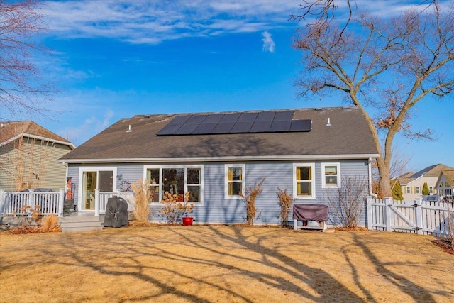 rear view of property with a lawn and solar panels