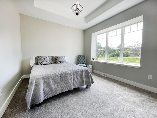 bedroom featuring a tray ceiling and dark carpet