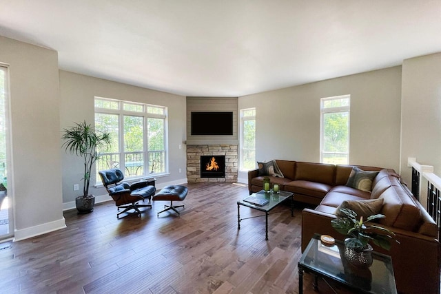 living room featuring dark wood-type flooring and a stone fireplace