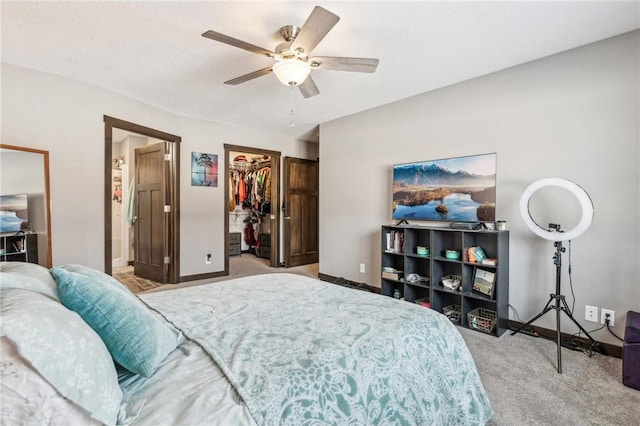 bedroom with ceiling fan, a textured ceiling, a spacious closet, light colored carpet, and a closet