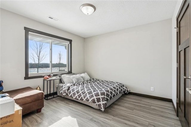 bedroom with a textured ceiling and light wood-type flooring