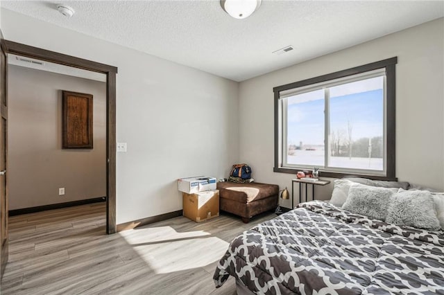 bedroom featuring light hardwood / wood-style floors and a textured ceiling