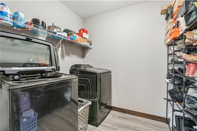 laundry area with light hardwood / wood-style floors, washing machine and dryer, and a textured ceiling