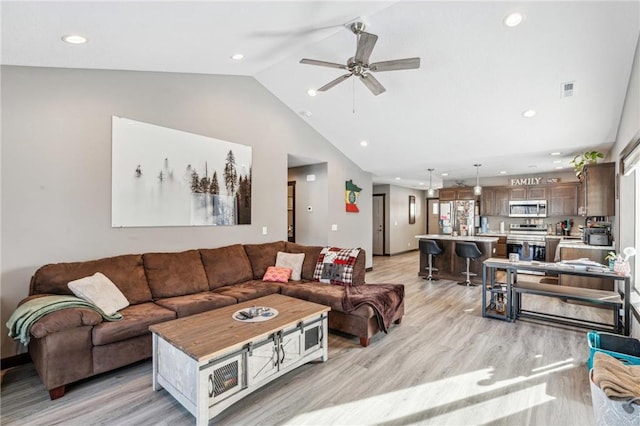 living room featuring ceiling fan, light hardwood / wood-style floors, and vaulted ceiling