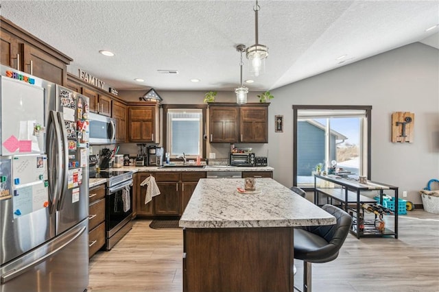 kitchen featuring vaulted ceiling, pendant lighting, sink, a center island, and stainless steel appliances