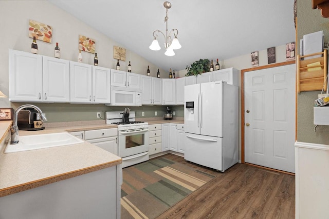 kitchen with sink, white appliances, white cabinets, decorative light fixtures, and vaulted ceiling