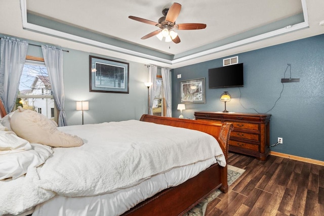 bedroom featuring dark wood-type flooring, ceiling fan, and a tray ceiling