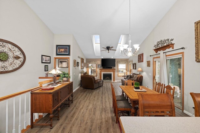 dining room featuring hardwood / wood-style floors, ceiling fan with notable chandelier, a skylight, and high vaulted ceiling