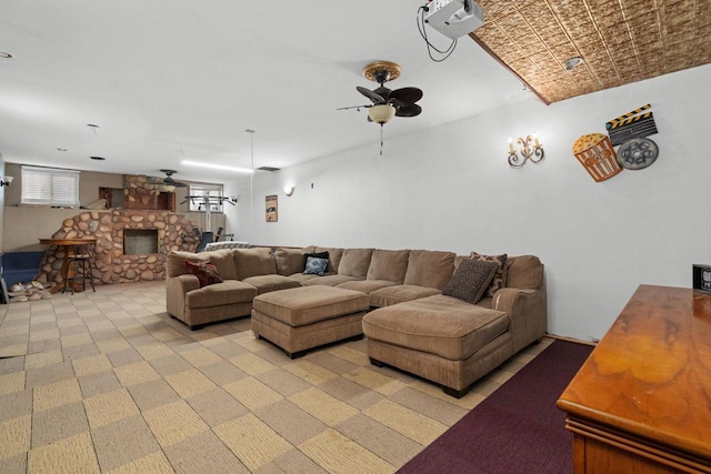 carpeted living room featuring ceiling fan and a stone fireplace