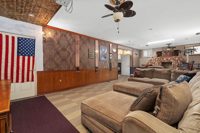 living room with a fireplace, wooden walls, and ceiling fan