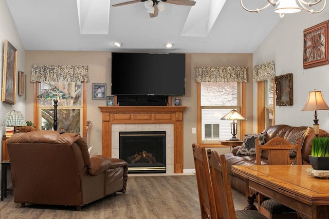 living room with a tiled fireplace, hardwood / wood-style floors, vaulted ceiling, and ceiling fan