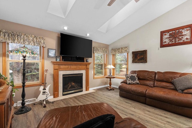 living room with a fireplace, lofted ceiling with skylight, and light hardwood / wood-style flooring