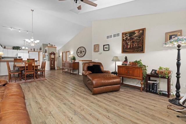 living room with ceiling fan with notable chandelier, high vaulted ceiling, and light hardwood / wood-style floors