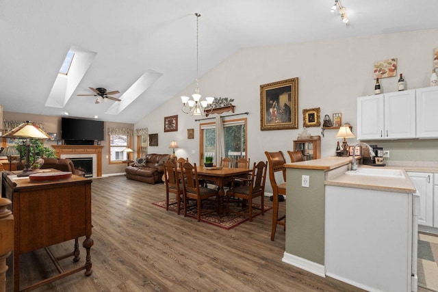 dining space featuring sink, a notable chandelier, lofted ceiling with skylight, and dark hardwood / wood-style floors