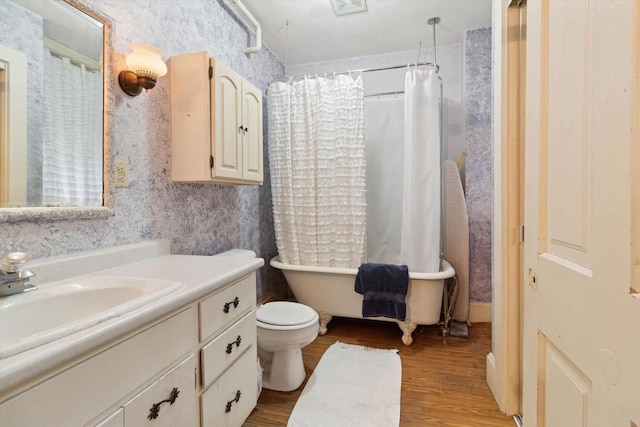 126 E Washington St, Stoughton, WI 53589 - full bath with wood finished floors, a freestanding tub, vanity, toilet, and wallpapered walls