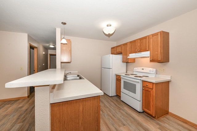 kitchen with white appliances, light hardwood / wood-style flooring, decorative light fixtures, and a breakfast bar area