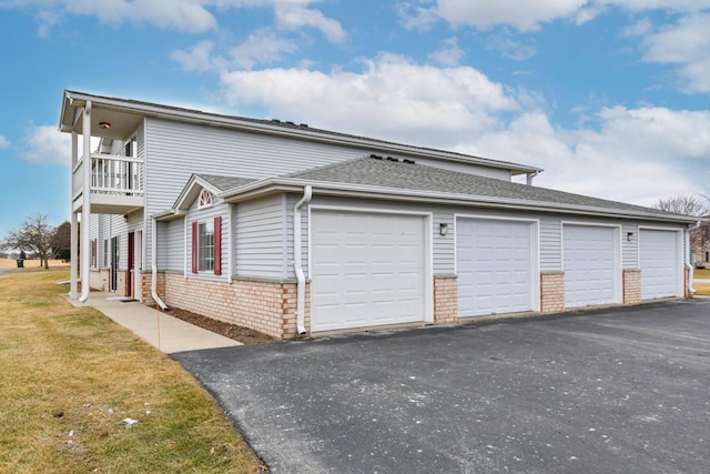 exterior space featuring a garage, a balcony, and a lawn