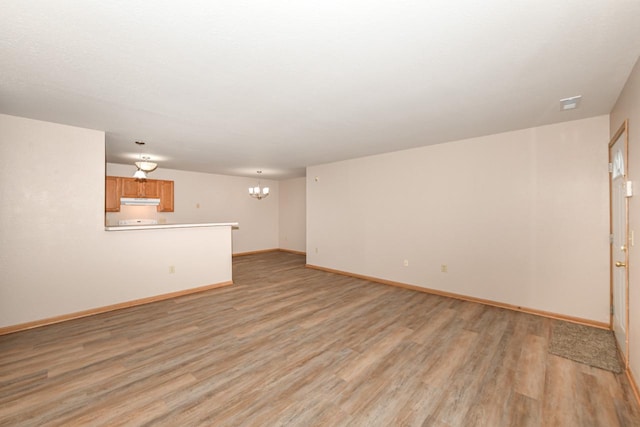 unfurnished living room featuring a notable chandelier and light hardwood / wood-style floors