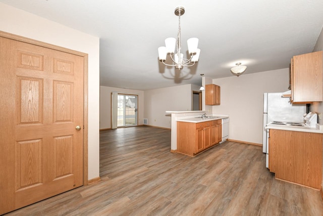 kitchen featuring pendant lighting, white appliances, sink, and light hardwood / wood-style floors