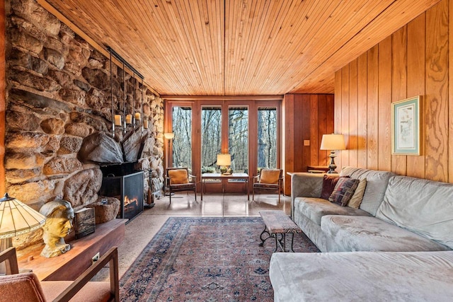 living room with wood walls, a stone fireplace, and wooden ceiling