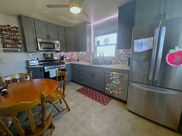 kitchen with sink, gray cabinets, ceiling fan, stainless steel appliances, and tasteful backsplash