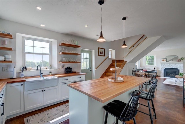 kitchen featuring pendant lighting, white cabinetry, sink, wooden counters, and a kitchen breakfast bar