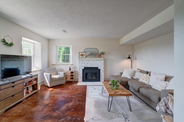 living room featuring a stone fireplace and a textured ceiling