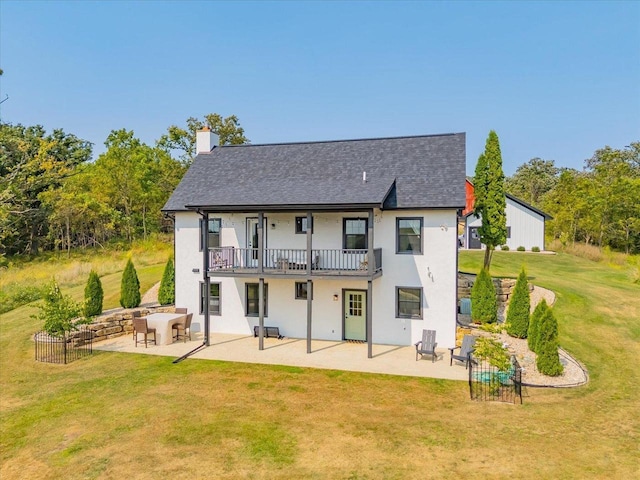 rear view of property with a balcony, a lawn, and a patio area