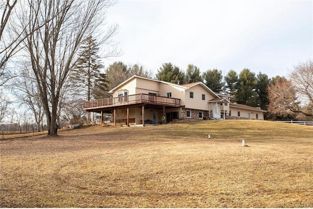 back of property with a wooden deck and a lawn