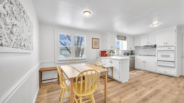 kitchen featuring extractor fan, white cabinetry, light wood-type flooring, stainless steel dishwasher, and oven