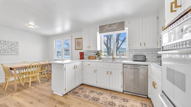 kitchen featuring dishwasher, white cabinets, light hardwood / wood-style floors, kitchen peninsula, and white oven