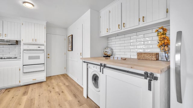 clothes washing area featuring washer / dryer and light hardwood / wood-style floors