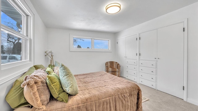 bedroom featuring light colored carpet and multiple closets