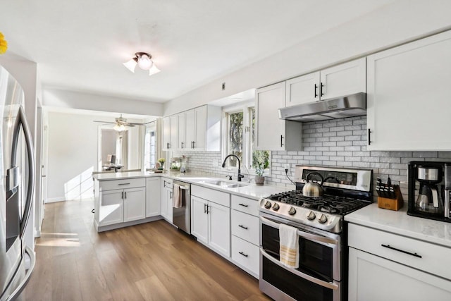 kitchen featuring sink, white cabinetry, light wood-type flooring, stainless steel appliances, and backsplash