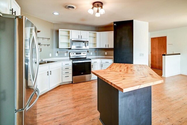 kitchen featuring visible vents, butcher block counters, light wood-style flooring, stainless steel appliances, and open shelves