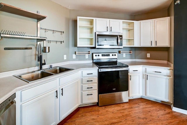 kitchen featuring light wood finished floors, open shelves, a sink, white cabinets, and appliances with stainless steel finishes