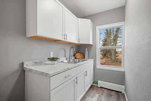 bar featuring a baseboard heating unit, sink, a wealth of natural light, and white cabinets